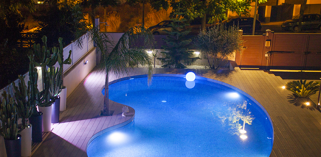 Vista general nocturna de terrassa amb piscina.